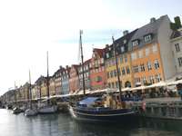 Copenhagen Nyhavn Harbour: Small boats in the harbour, behind them the boulevard with restaurants and old houses.